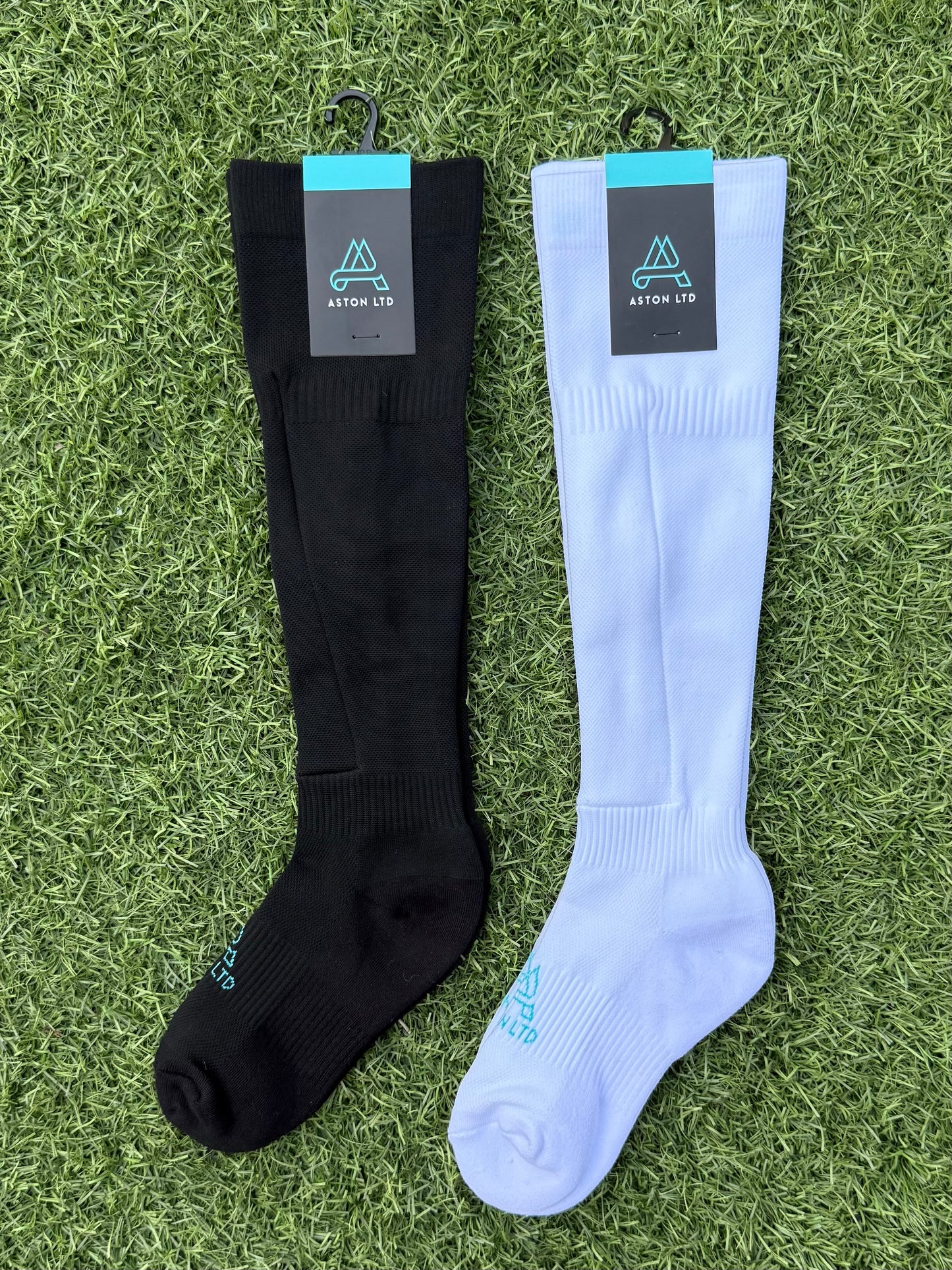Black and white knee-high socks with shin guard pocket. Brand labels on a grass background