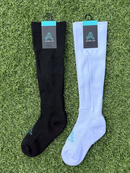 Black and white knee-high socks with shin guard pocket. Brand labels on a grass background